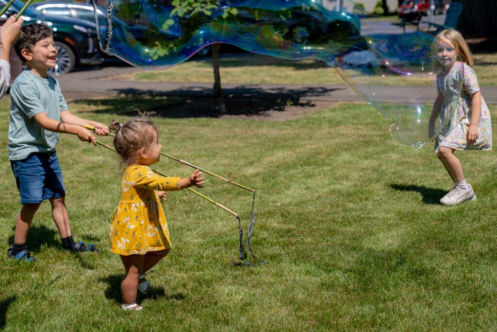 Children chasing a giant bubble in the park.